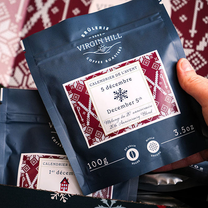 Hand holding a coffee package with a festive design against a patterned background