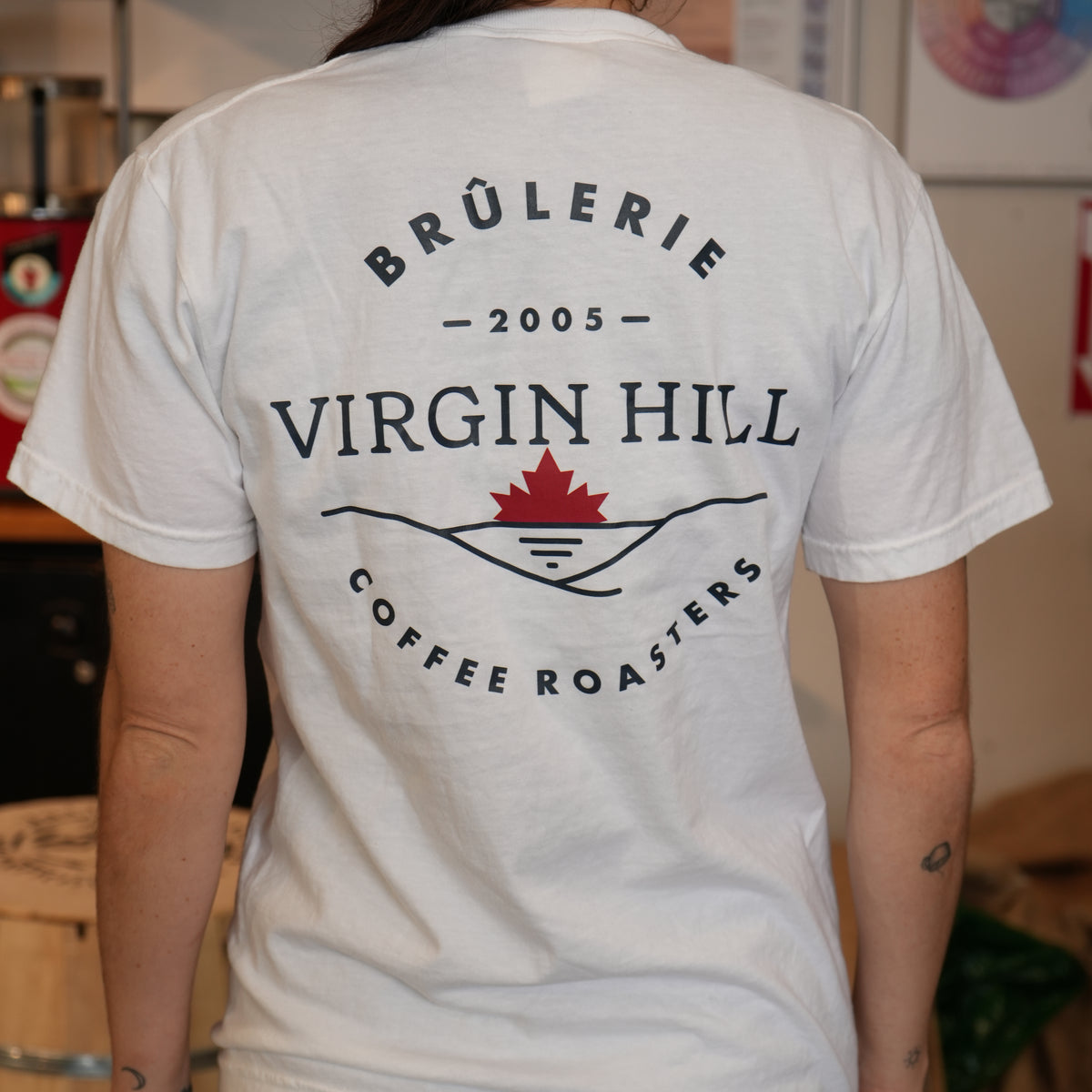 Person wearing a white t-shirt with 'Brélèrie Virgin Hill Coffee Roasters' logo.
