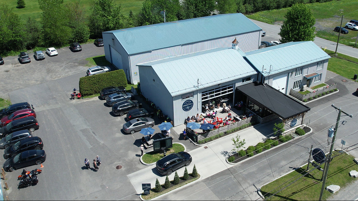 A large building with a parking lot and people gathered outside on a sunny day.