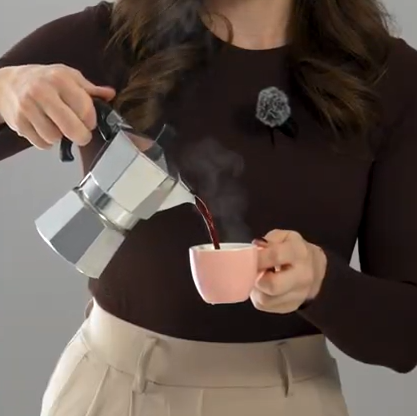 Person pouring coffee from a French press into a pink cup.